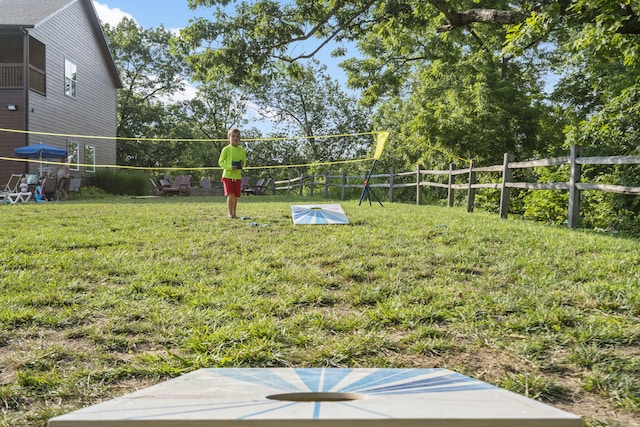 view of home's community with volleyball court, a lawn, and fence