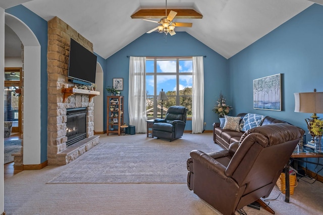 carpeted living area with arched walkways, vaulted ceiling, a fireplace, and baseboards