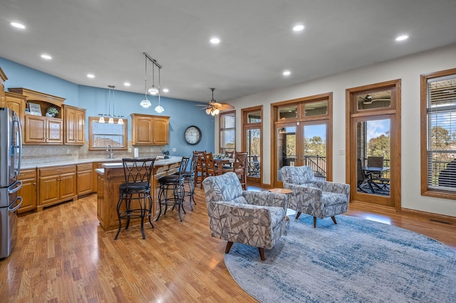 kitchen with decorative backsplash, a breakfast bar, a center island, light countertops, and light wood-style floors