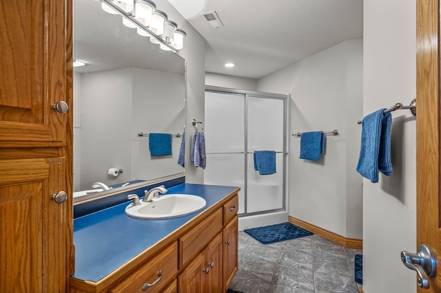 bathroom with vanity, a shower stall, visible vents, and baseboards