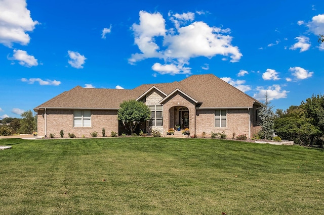 ranch-style home featuring brick siding, roof with shingles, and a front yard