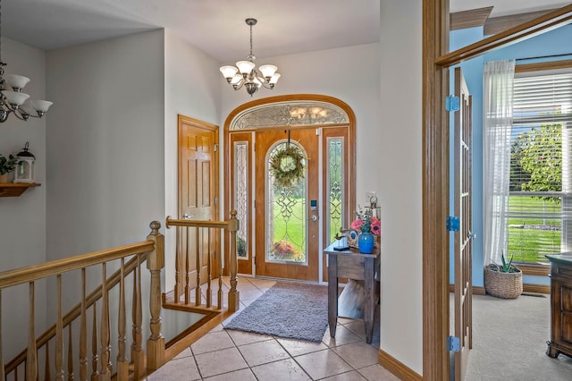 foyer entrance with baseboards, light tile patterned flooring, and a notable chandelier