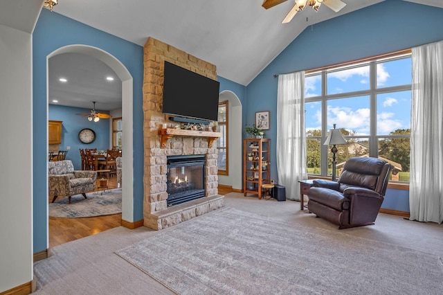 sitting room featuring arched walkways, a fireplace, ceiling fan, and carpet flooring