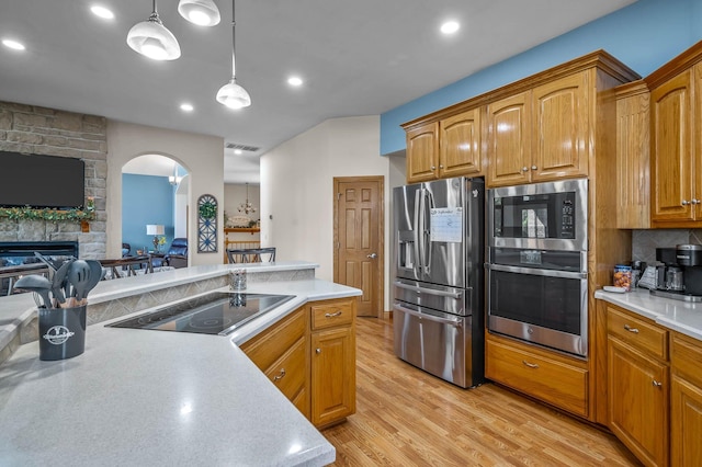 kitchen featuring light countertops, appliances with stainless steel finishes, a fireplace, and light wood-style flooring