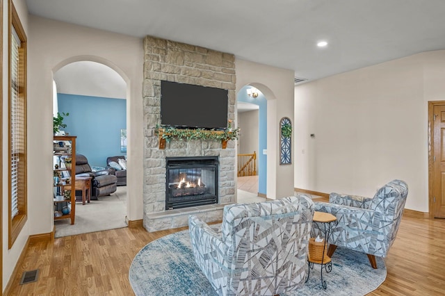 living room featuring visible vents, a fireplace, baseboards, and wood finished floors