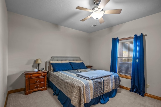 bedroom with light carpet, a ceiling fan, visible vents, and baseboards