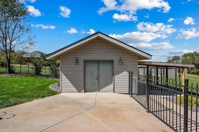 view of outdoor structure with an outbuilding, driveway, and fence