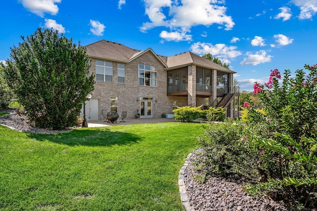 rear view of property featuring a patio, brick siding, and a lawn