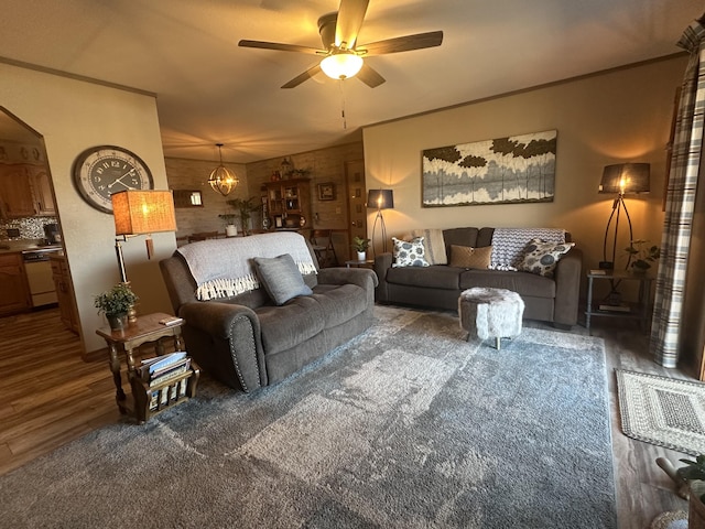 living room with crown molding, wood finished floors, and ceiling fan with notable chandelier