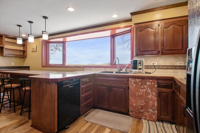 kitchen with a kitchen bar, light wood-type flooring, ornamental molding, black appliances, and a sink