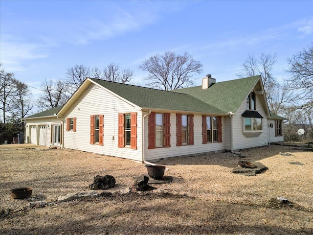 exterior space with a chimney, a garage, and a shingled roof