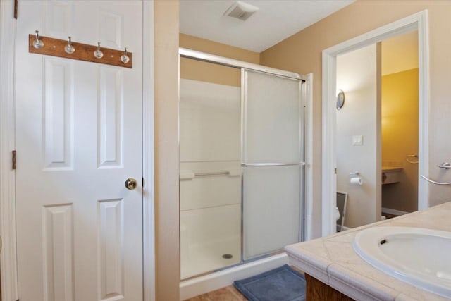 bathroom with vanity, a shower stall, toilet, and visible vents