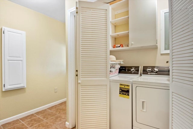 laundry area with light tile patterned floors, cabinet space, washer and dryer, and baseboards