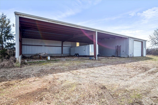 view of parking / parking lot with driveway, a garage, and a pole building