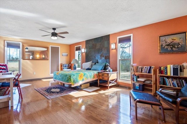 bedroom with baseboards, wood-type flooring, and a textured ceiling