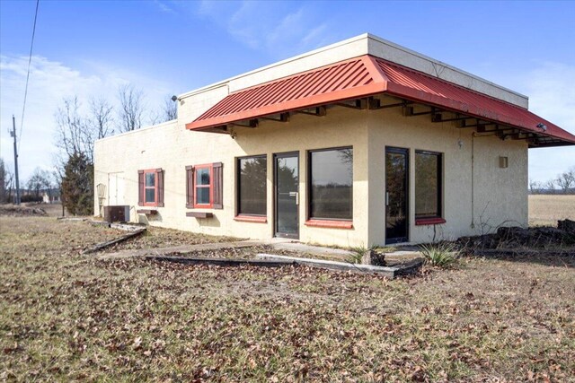 rear view of house with stucco siding, metal roof, and a standing seam roof