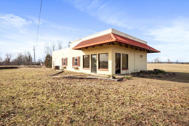 back of house with stucco siding and central AC