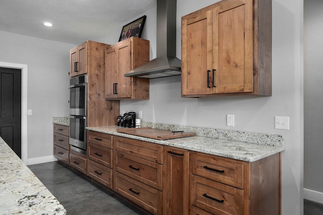 kitchen featuring wall chimney range hood, stainless steel double oven, cooktop, and brown cabinets