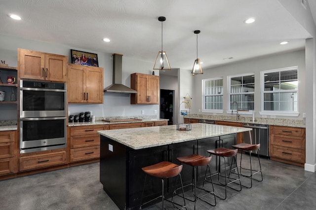 kitchen featuring concrete flooring, stainless steel appliances, a kitchen breakfast bar, wall chimney range hood, and a center island