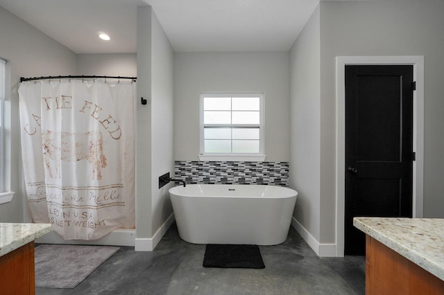 bathroom featuring concrete flooring, a soaking tub, vanity, and baseboards