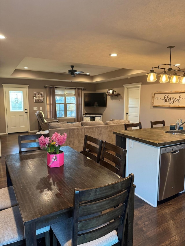 dining space featuring a tray ceiling, dark wood-type flooring, and recessed lighting