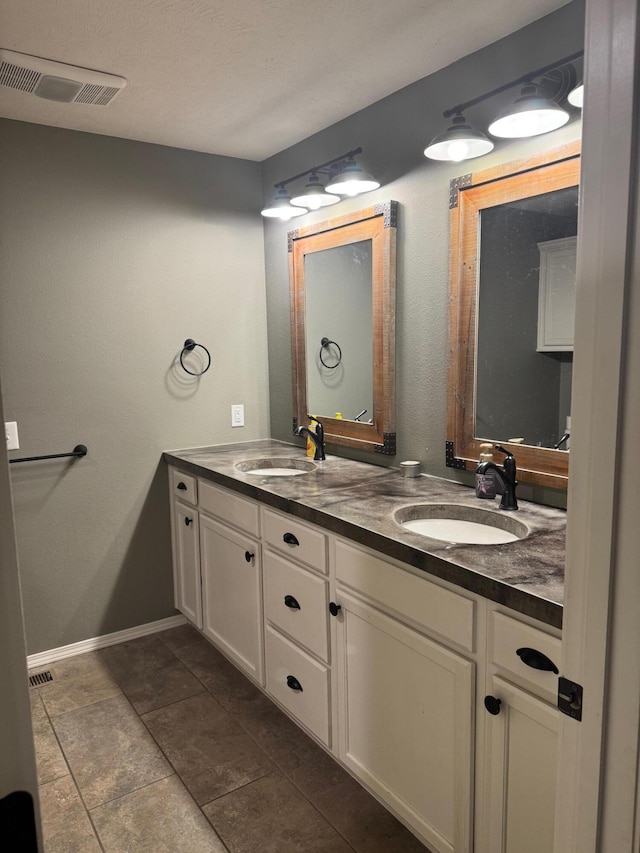 full bathroom featuring double vanity, a sink, visible vents, and baseboards