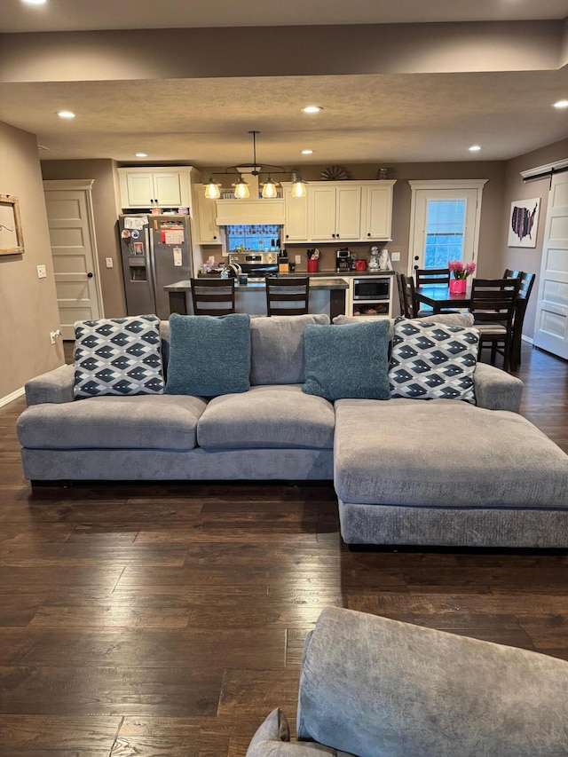 living area with dark wood-style floors, recessed lighting, baseboards, and a barn door