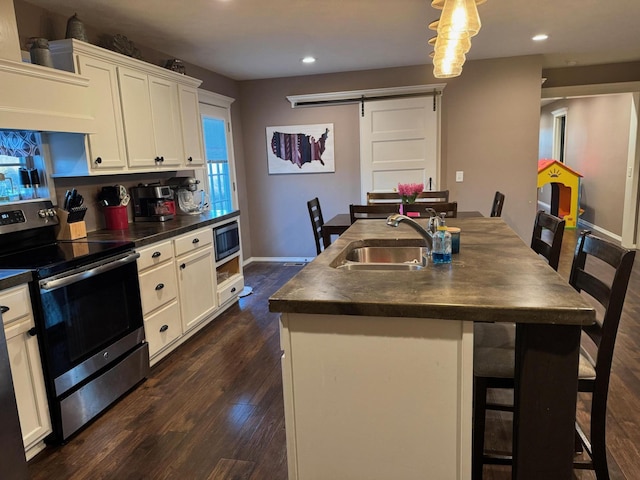 kitchen featuring dark countertops, stainless steel electric range oven, a sink, and a barn door