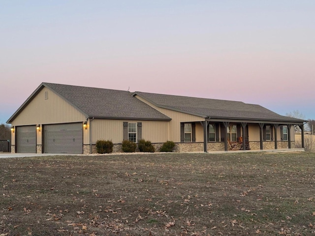 view of front facade with a garage, stone siding, a shingled roof, and concrete driveway