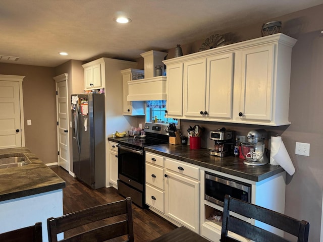 kitchen with dark wood-style floors, dark countertops, recessed lighting, appliances with stainless steel finishes, and white cabinets