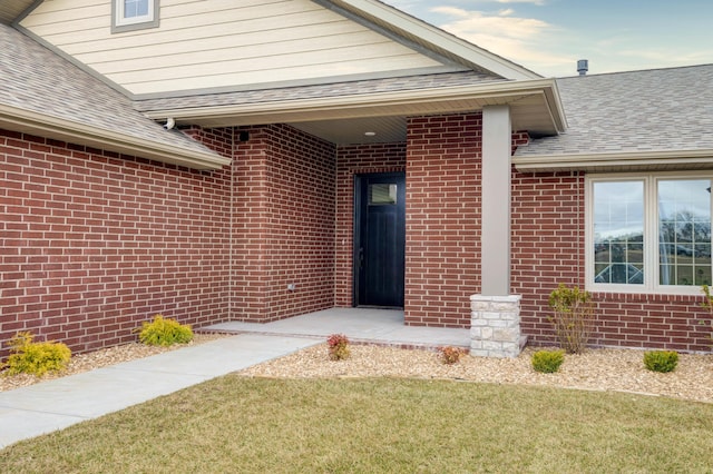 property entrance featuring a shingled roof and brick siding