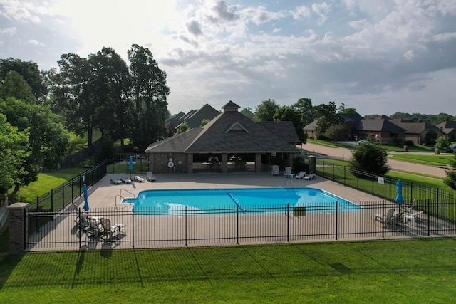 community pool featuring a patio area, a lawn, and fence