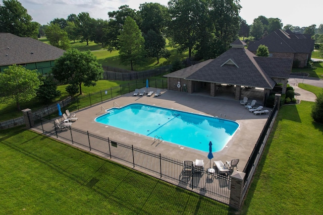 pool featuring a yard, a patio, and fence