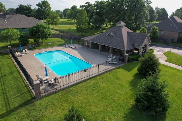 pool featuring fence, a lawn, an outbuilding, and a patio
