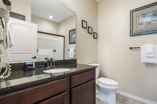 bathroom with toilet, vanity, baseboards, tile patterned floors, and a shower with door