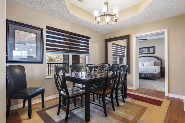 dining room with a chandelier, a textured ceiling, baseboards, and wood finished floors