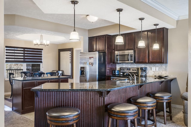 kitchen with a peninsula, tasteful backsplash, stainless steel appliances, and a sink