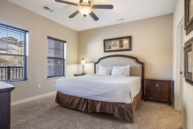 carpeted bedroom featuring baseboards, a textured ceiling, visible vents, and a ceiling fan