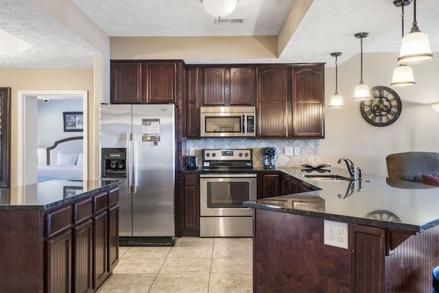 kitchen featuring stainless steel appliances, a peninsula, a sink, visible vents, and backsplash