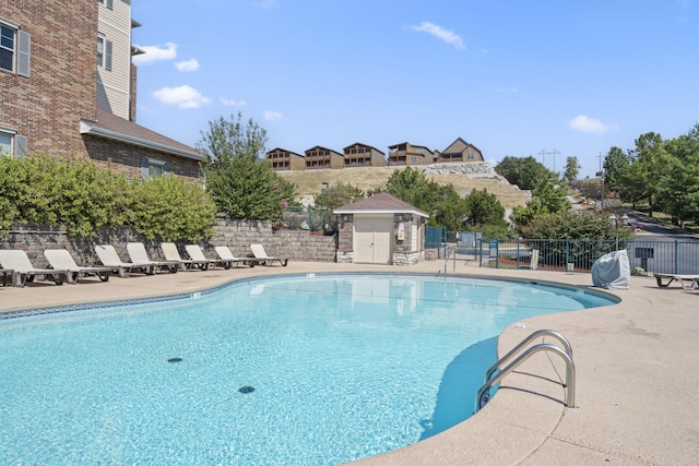 community pool featuring an outbuilding, a patio, and fence