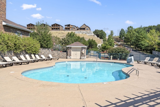 community pool with a patio and fence