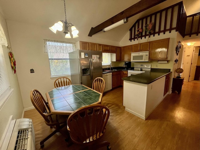 kitchen featuring white appliances, wood finished floors, beamed ceiling, a peninsula, and a notable chandelier