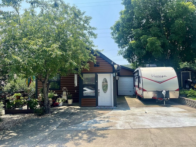 view of front of house with driveway, a garage, and faux log siding