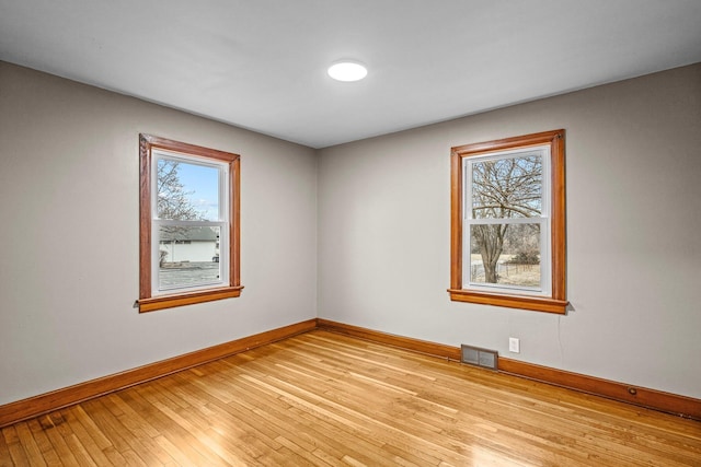 unfurnished room with baseboards, visible vents, and light wood finished floors