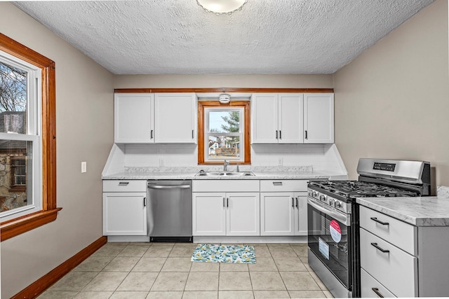 kitchen featuring stainless steel appliances, light countertops, white cabinetry, a sink, and light tile patterned flooring