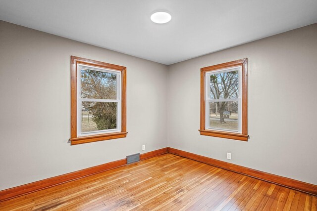 spare room with baseboards, visible vents, and light wood-style floors