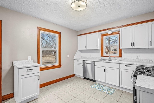 kitchen with baseboards, white cabinets, a sink, stainless steel appliances, and backsplash