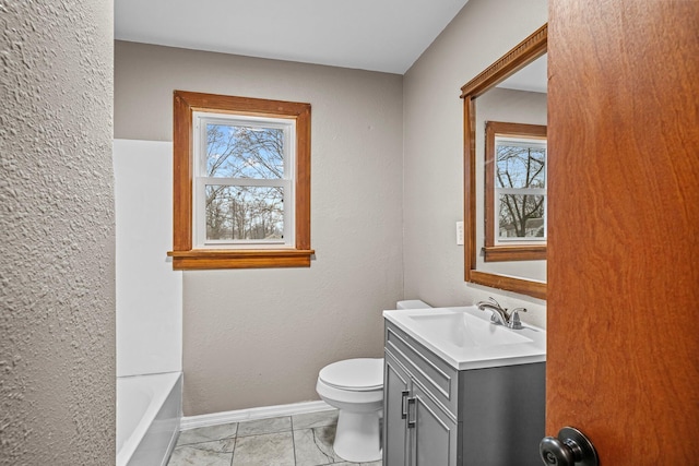 full bath with baseboards, a textured wall, toilet, a bathtub, and vanity