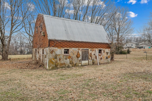 view of side of home with an outbuilding, metal roof, a barn, a gambrel roof, and stone siding