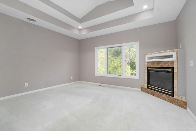 unfurnished living room with a fireplace, carpet flooring, visible vents, baseboards, and a raised ceiling